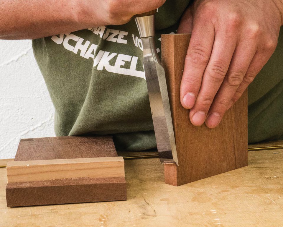 Mit dem Stemmeisen werden kleine Holzstückchen abgetrennt.