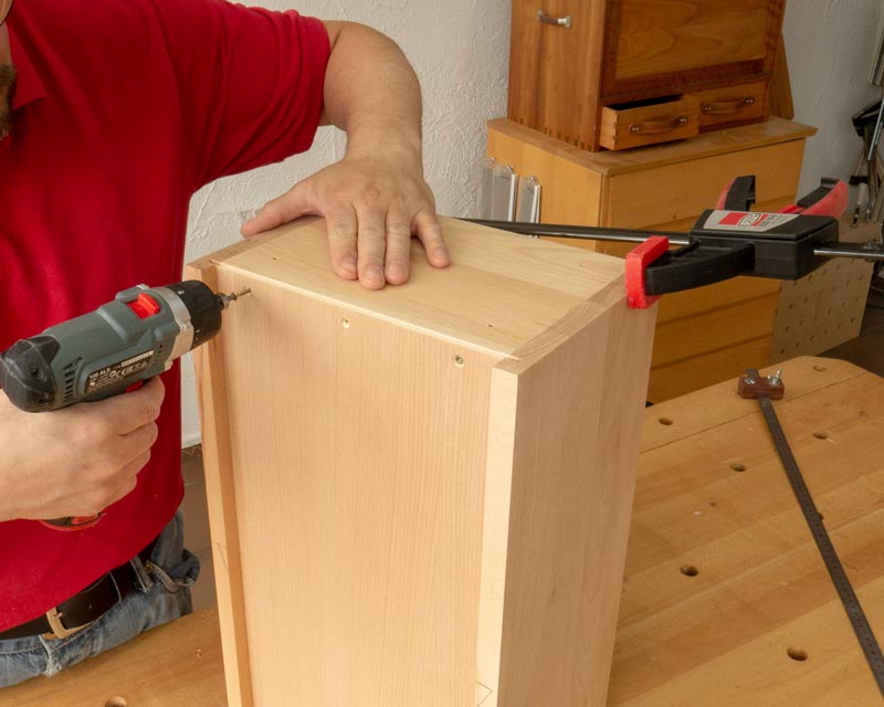 Ist der Korpus in Position gedrückt, verschraubt man die Rückwand fertig. Der Winkel bleibt dann auch nach dem Lösen der Zwinge so.