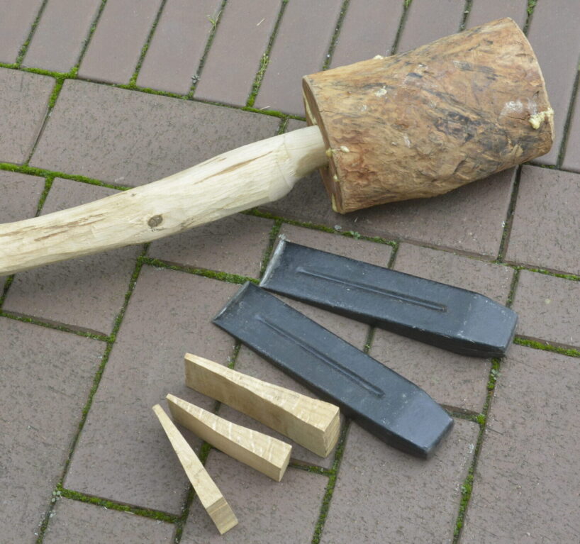 Ein Holzhammer liegt neben Holz- und Alukeilen.