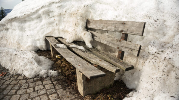 Verwitterte Gartenbank draußen im Schnee.